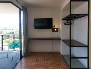 a room with a tv and shelves and a balcony at Hotel Macaw Cúcuta in Cúcuta