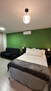 a bedroom with a large bed with a green wall at Pousada Flor de Piri in Pirenópolis +30 photos