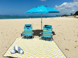 檀香山Ocean View Oasis with Free Parking, A Waikiki Gem!的海滩上一把遮阳伞下的两把椅子