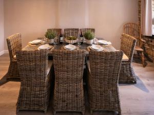 una mesa con sillas de mimbre y una mesa con platos y cuencos en Yew Tree Cottage, en Broadway