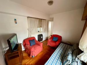 a bedroom with two red chairs and a television at Departamento de 3 ambientes in La Porteña