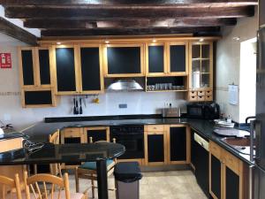 a kitchen with wooden cabinets and a black counter top at Alojamiento Costa Quebrada in Soto de la Marina