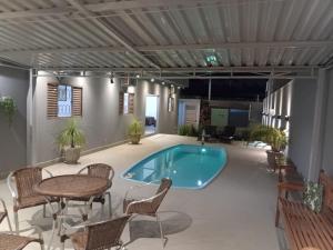 a swimming pool in a patio with chairs and a table at casa inteira com 3 suites e área de lazer in Delfinópolis