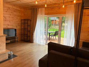 a living room with a couch and a television at Dadajówka Domki przy plaży in Wilimy