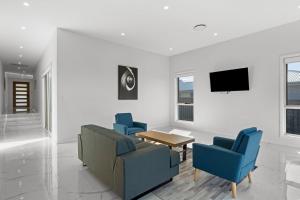 Una sala de estar con sillas azules, una mesa y un televisor. en Cork & Vine on Coolalta - A Cellar Door Escape, en Nulkaba