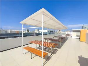 eine Gruppe von Tischen und Bänken auf einem Dach in der Unterkunft DEPARTAMENTO con BALCÓN DE 3 HABITACIONES CERCA DE TODO in Chiclayo