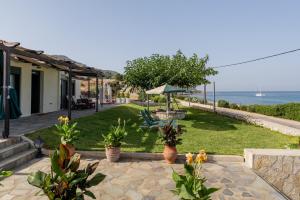 a patio with a lawn with a view of the ocean at Orianthi's Beachfront Home in Skala
