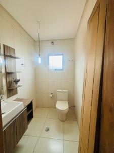 a bathroom with a toilet and a sink and a window at Casa Hostel Léami in Guarulhos +21 photos