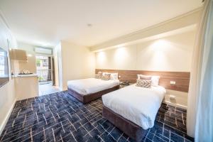 ミルデューラにあるCommodore Motel Milduraのベッドが2つと鏡があるホテルの部屋