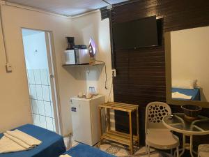 a small room with a refrigerator and a table and a tv at Casa da Silvana in Fernando de Noronha