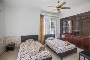 une chambre avec deux lits et un ventilateur de plafond dans l'établissement Villa Mavris - Lovely 4 Bedroom Villa With Private Pool In Central Ayia Napa, à Ayia Napa 14 autres photos