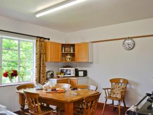 a kitchen with a table and chairs and a clock at The Old Post Office in Eaton Bishop