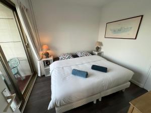 ein Schlafzimmer mit einem weißen Bett mit zwei blauen Kissen in der Unterkunft Arsène 3 l'Hermitage in Le Touquet-Paris-Plage