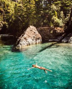 a person laying in the water in a river at Cabaña de la flor in El Bolsón
