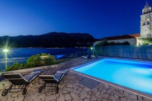 a pool on the roof of a building with chairs and a lighthouse at Fantastic Seafront Villa 4 Bedrooms Villa Samostan Prestige Stunning Sea Views & Enclosed Garden With Private Pool Korcula in Korčula