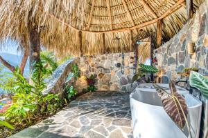 a resort room with a thatched roof and a patio at The Bird Nest at Casa Paloma in San Marcos La Laguna