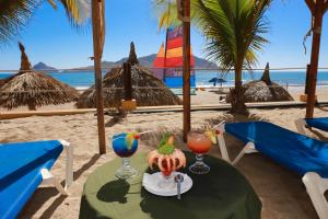 Una mesa con dos bebidas en la playa en Las Flores Beach Resort, en Mazatlán
