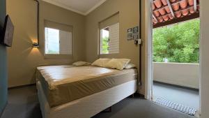 a small bedroom with a bed and a window at Suíte 15 • Praia das Pitangueiras in Guarujá