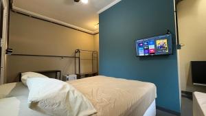 a hospital room with a bed and a flat screen tv at Suíte 15 • Praia das Pitangueiras in Guarujá