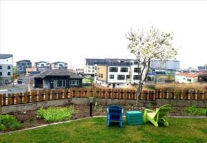 a yard with two chairs and a tree and a fence at Jeju Badamjeong in Jeju