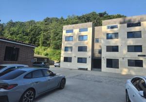 Un coche aparcado en un estacionamiento frente a un edificio. en Uljin Serendipity Pension, en Paeksŏk