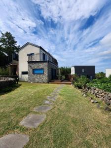 a stone house with a balcony on top of a yard at Hallim House in Jeju