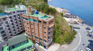 a building on the side of a hill next to the water at Sokcho Travel Hotel in Sokcho