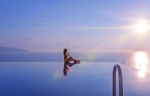 a person sitting on the edge of a swimming pool at Apec Mandala Harmony Resort & Spa in Mui Ne