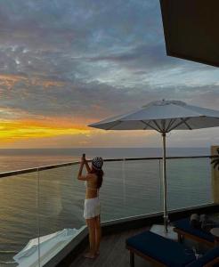 a woman standing on a balcony looking out at the ocean at Apec Mandala Harmony Resort & Spa in Mui Ne