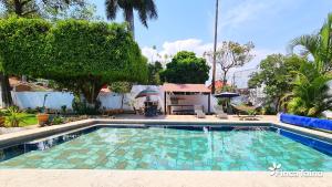 a swimming pool in a yard with trees and a building at Finca Taino. Hermosa casa con alberca in Jiutepec