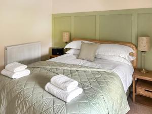 a bedroom with a large bed with towels on it at Tiddles Corner in Braunston