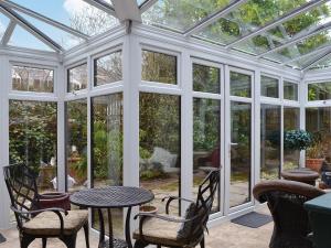 a conservatory with a table and chairs and glass doors at Ty Newydd in Beddgelert