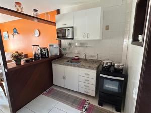 cocina pequeña con armarios blancos y fogones en Casa em frente a Praia das Dunas, Cabo Frio - RJ, en Cabo Frío