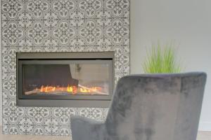 a fireplace with a chair in a living room at La Villa Bali in Pont-Rouge