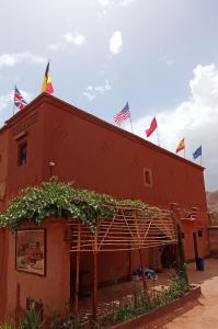 a red building with flags on top of it at Gite le Calme café Restaurant Pizzeria in Bou Tharar