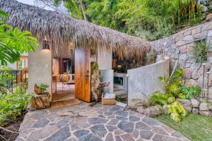 a house with a thatch roof and a stone wall at NEW! Jacuzzi, lake-access luxury in San Marcos La Laguna