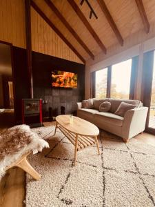 a living room with a couch and a coffee table at Casa Las Raíces - Relajo con tinaja y vista al volcán, a minutos de Corralco in Malalcahuello
