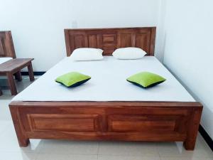 a bed with two green pillows on top of it at Igloo Tourist Homestay Anuradhapura in Anuradhapura