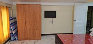 a bedroom with a television and a wooden cabinet at T&J Guest House in Rauis