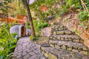 a stone path leading up to a house with a tree at Lake view paradise- waterfall, swim dock, kitchen in San Marcos La Laguna