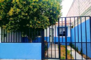 a blue fence in front of a building with a tree at Casa SUR in Colonia de Venado