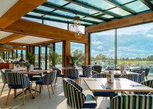 Un restaurante con mesas y sillas y grandes ventanales. en York Marina, en Naburn