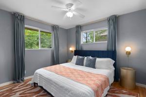 a bedroom with a bed with a ceiling fan and two windows at Cozy 5BR - Outdoor Theater, Fire Pit, Games in Westminster