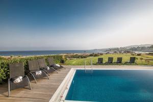 プロタラスにあるVilla Fig Tree Bay Frontline,Luxury 4Bdr Sea-Front Protaras Villa With Pool And Amazing Viewsの海を背景にスイミングプール(椅子付)