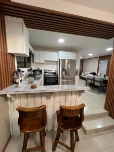 フォルトゥナにあるArenal Living Apartmentの白いキャビネットとバースツール2つ付きのキッチン