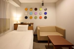 a room with a bed and a couch and a table at Via Inn Shin Osaka in Osaka