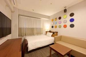 a hotel room with a bed and a couch at Via Inn Shin Osaka in Osaka