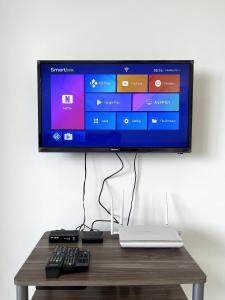 a television on a wall with a keyboard and a laptop at Cozy Homes at i-City WiFi TV Box and 1 Carpark in Shah Alam