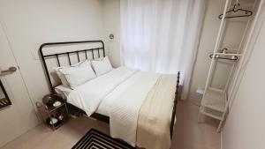 een bed met witte lakens en kussens in een slaapkamer bij Urban Retreat 3-Min Walk from Achasan Station, 15-Min to Seongsu, Tranquil Space for Relaxation in Seoul