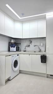 een keuken met witte kasten en een wasmachine en droger bij Urban Retreat 3-Min Walk from Achasan Station, 15-Min to Seongsu, Tranquil Space for Relaxation in Seoul